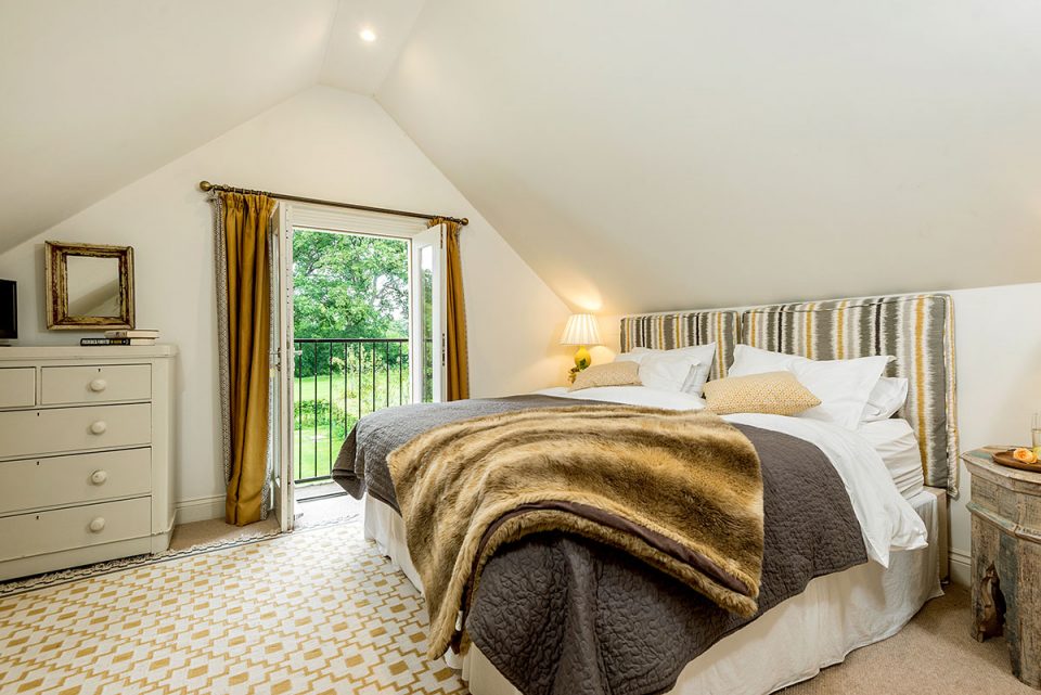 Geiger bedroom with pretty Juliet balcony and views over to the cider orchards. Luxury self-catering accommodation in Herefordshire | Monnington House and Cottages