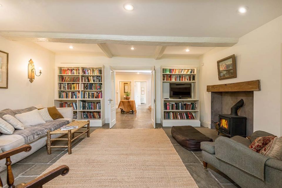 The snug with full bookshelves, comfy Howard chair and sofa and roaring woodburner