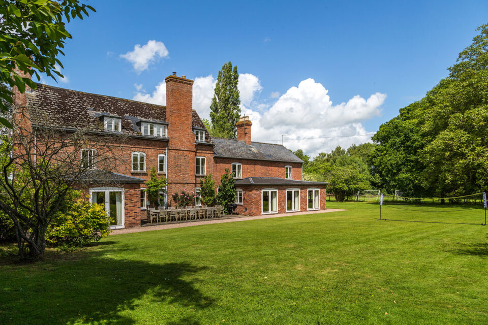 South side of Monnington House with large terrace, badminton on the lawn and the playing field in the distance